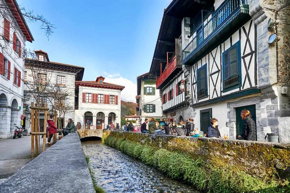 Vista del río, terrazas con gente tomando algo, y algunas bonitas fachadas de las casas del pueblo